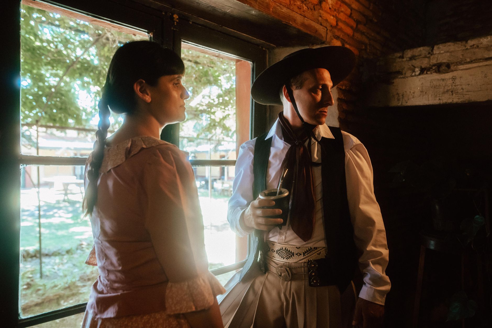 Argentine gaucho indoors holding mate, showcasing traditional clothing and culture.