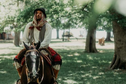Free A gaucho in traditional attire riding a horse through a sunlit Argentinian forest. Stock Photo