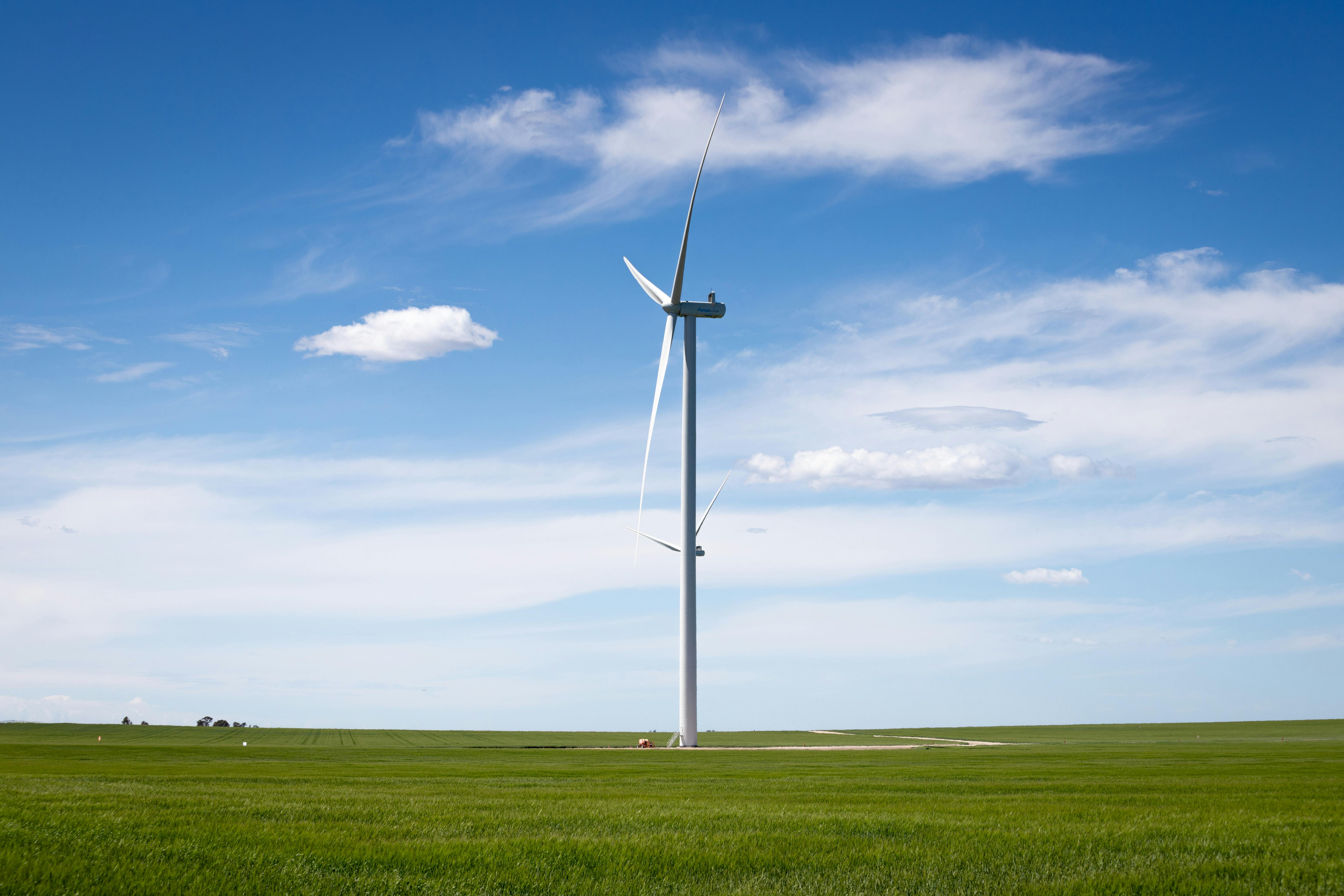 wind turbine in green field under blue sky