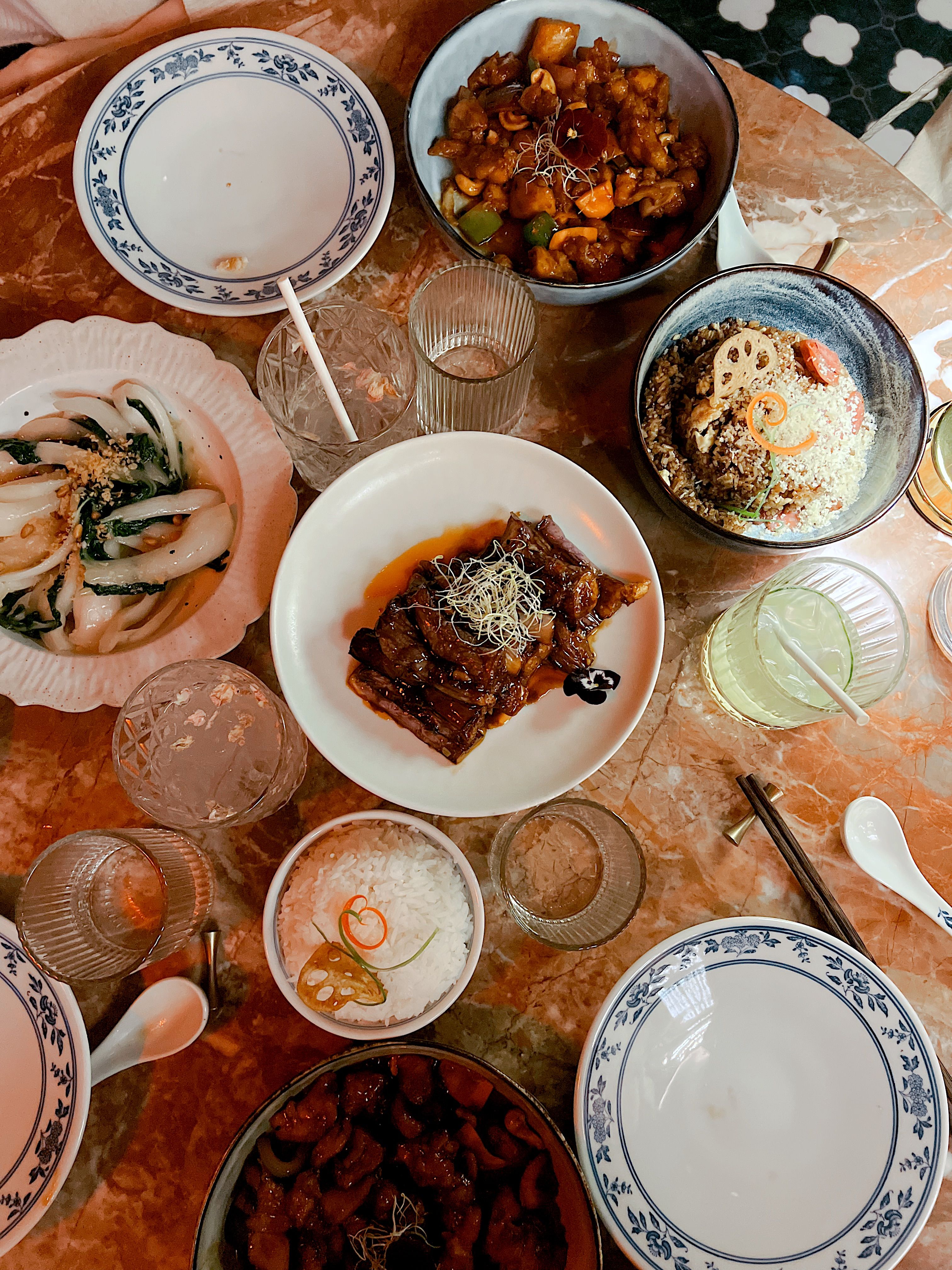 Table vue de haut : bœuf en sauce, riz sauté, légumes verts, baguettes et bols