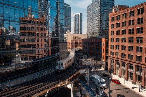 Free Modern cityscape featuring a train curving through Chicago's skyscrapers with bright lighting. Stock Photo