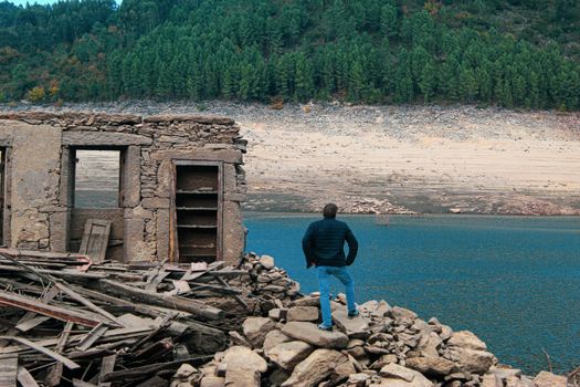 A man stands on ruins overlooking the drying village of Aceredo, Espanha.