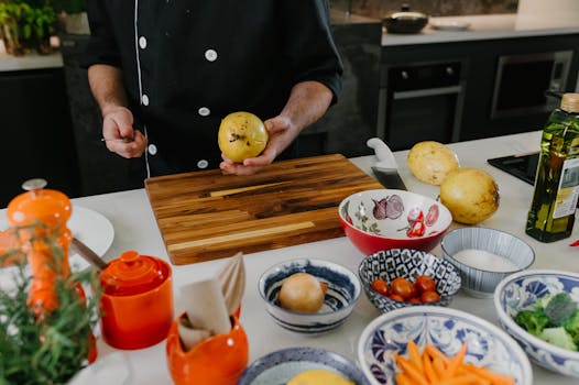 A chef in a modern kitchen setting prepares fresh ingredients on a wooden cutting board.