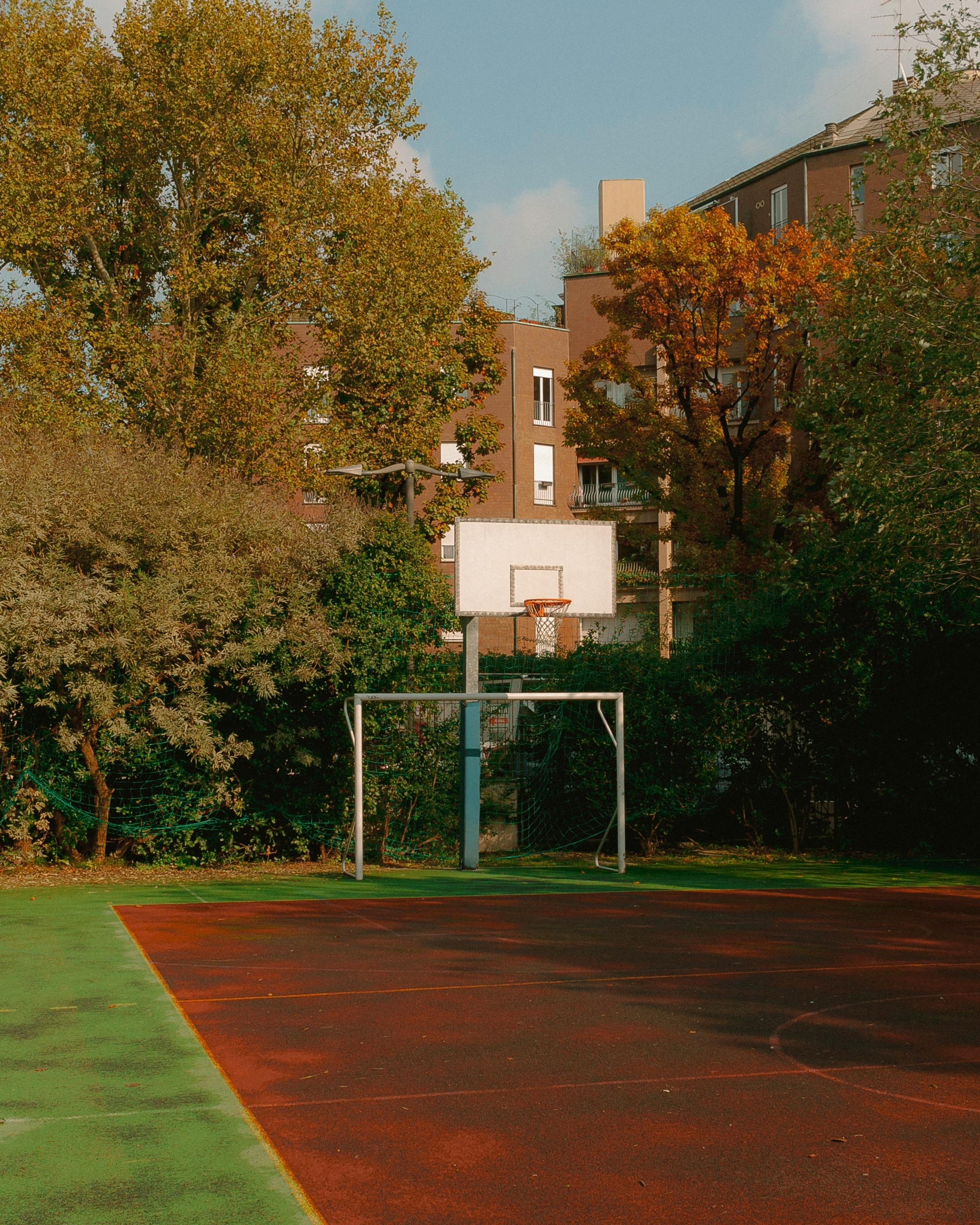 Scenic view of an empty basketball court surrounded by trees and buildings in Milano, Italy.