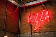 醒目的霓虹灯披萨标志为质朴的砖墙增添了魅力，照亮了墙面