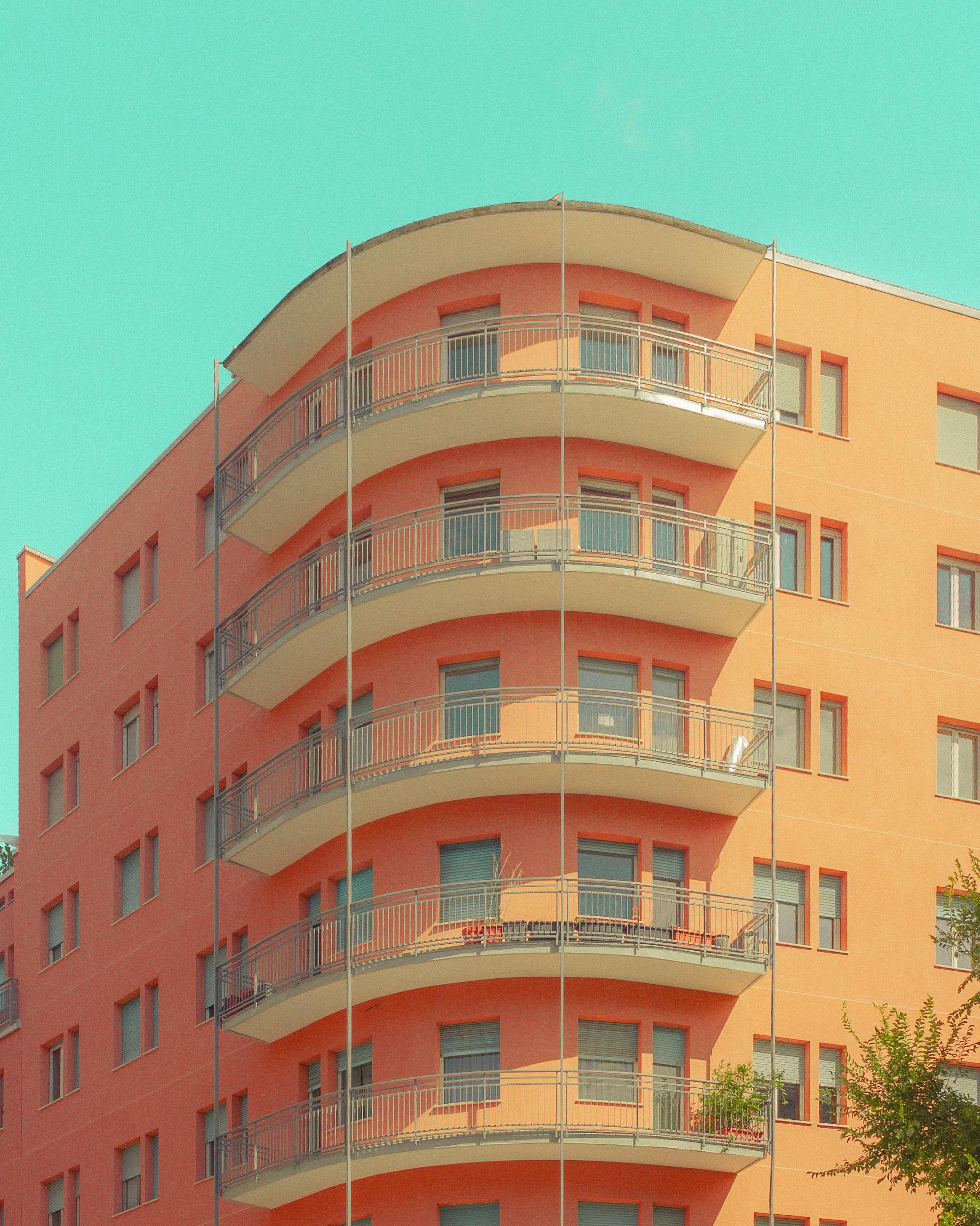 Curved balcony facade of modern apartment building under bright sky.