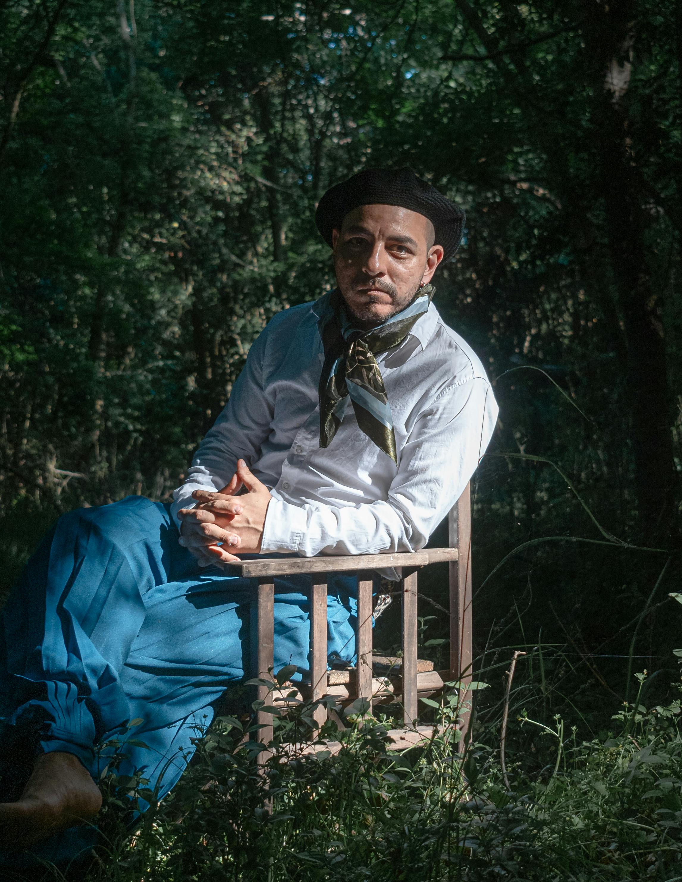 A traditional gaucho in classic attire enjoys a serene moment in a lush forest in Chascomús, Argentina.