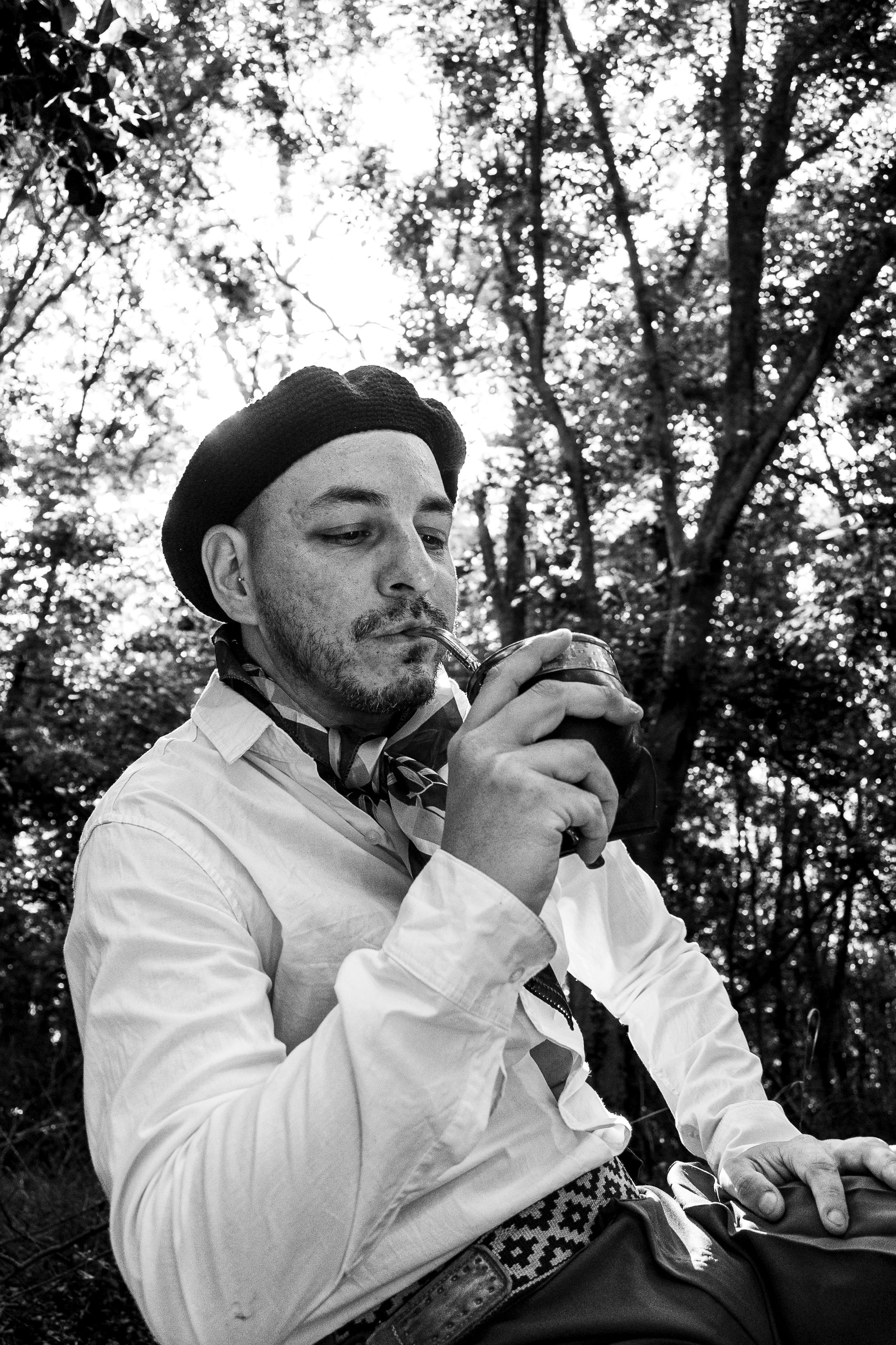 Black and white portrait of Argentine gaucho sipping mate outdoors.