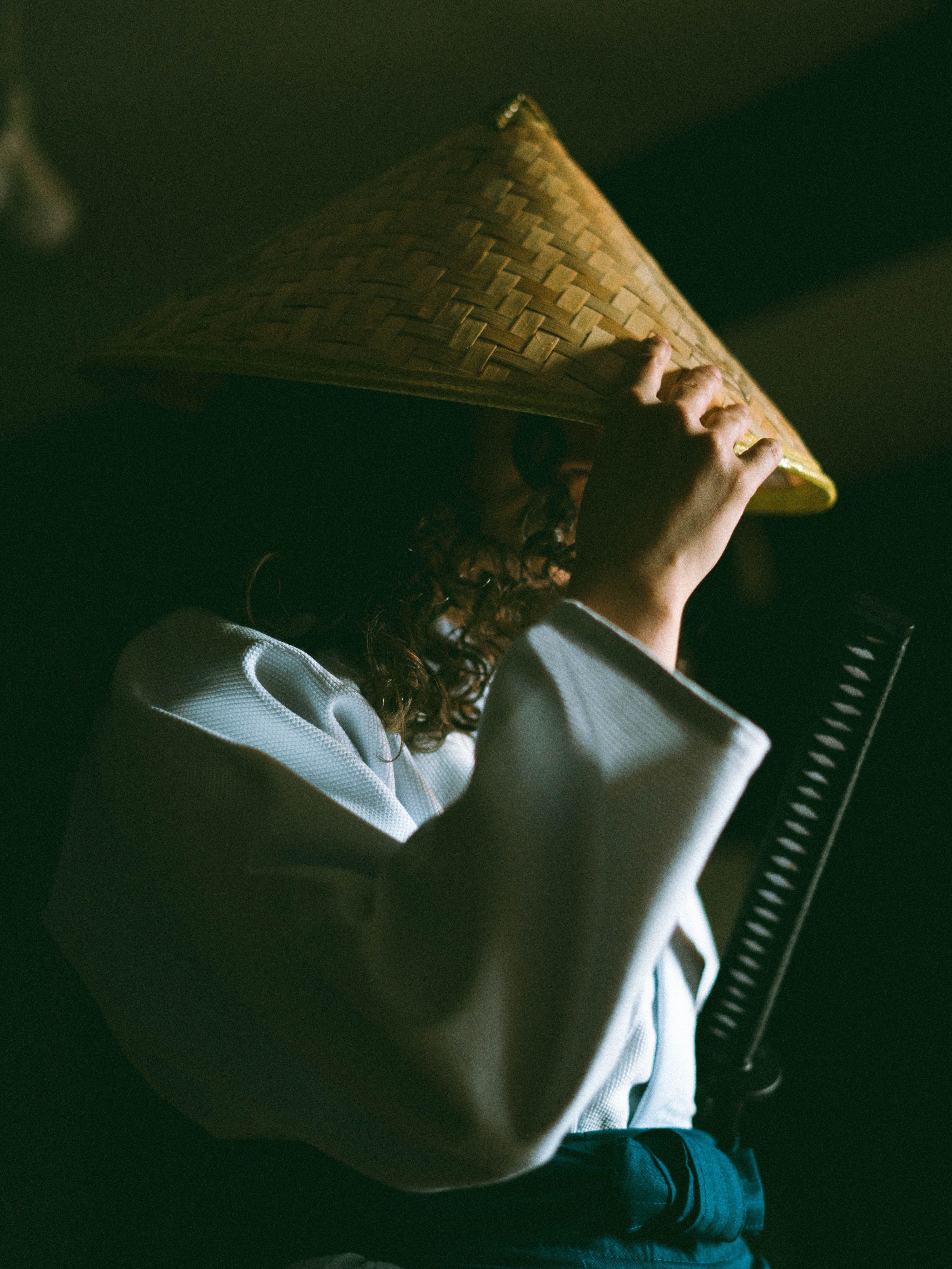 A person dressed in samurai attire and straw hat depicted in dramatic low light.