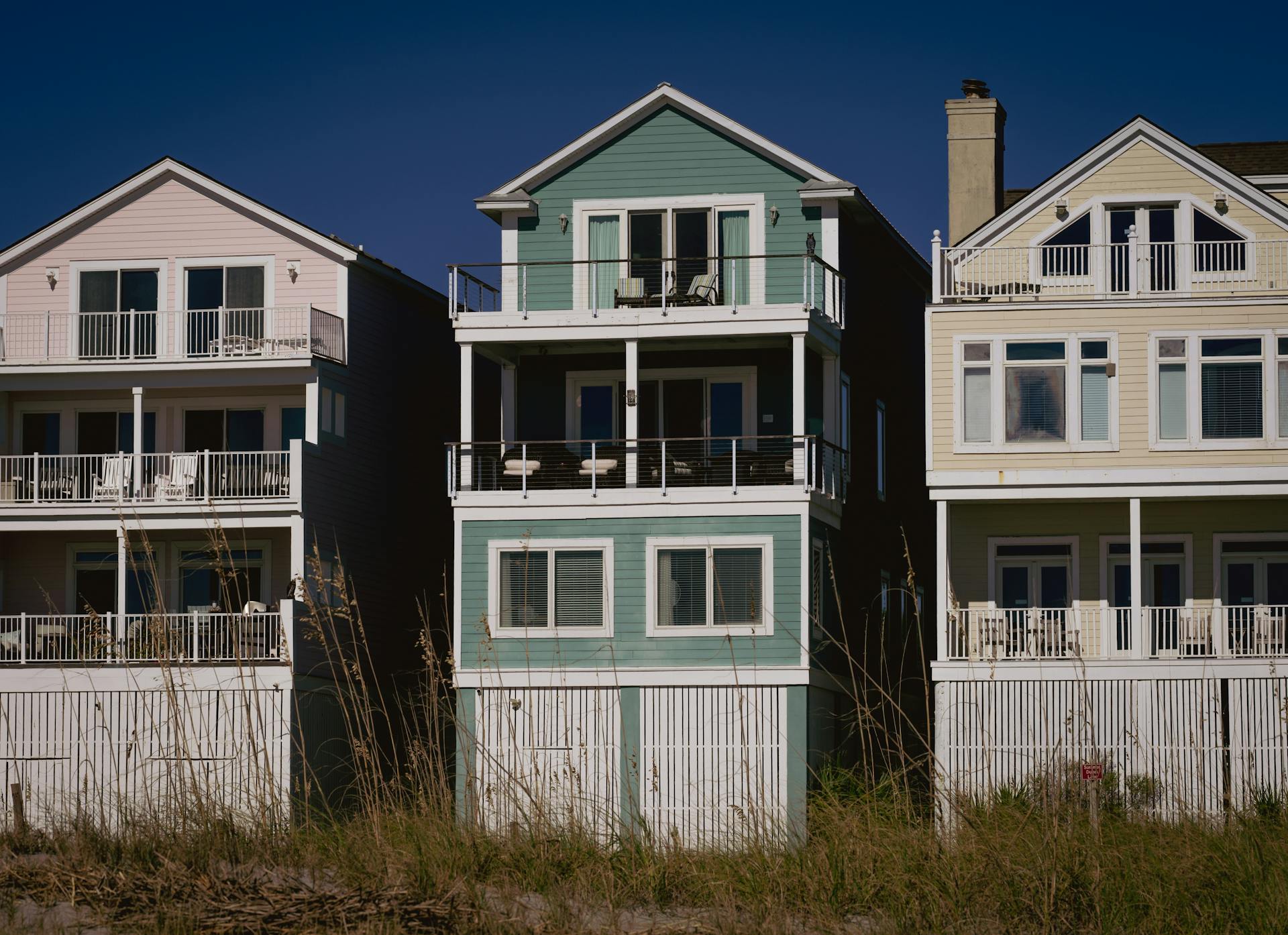 Sunny day view of colorful coastal homes with wooden siding and balconies, perfect for summer living.