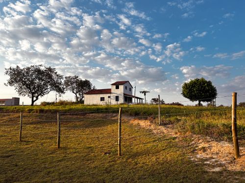 Free Picturesque view of a countryside house with fluffy clouds and vibrant landscape. Stock Photo