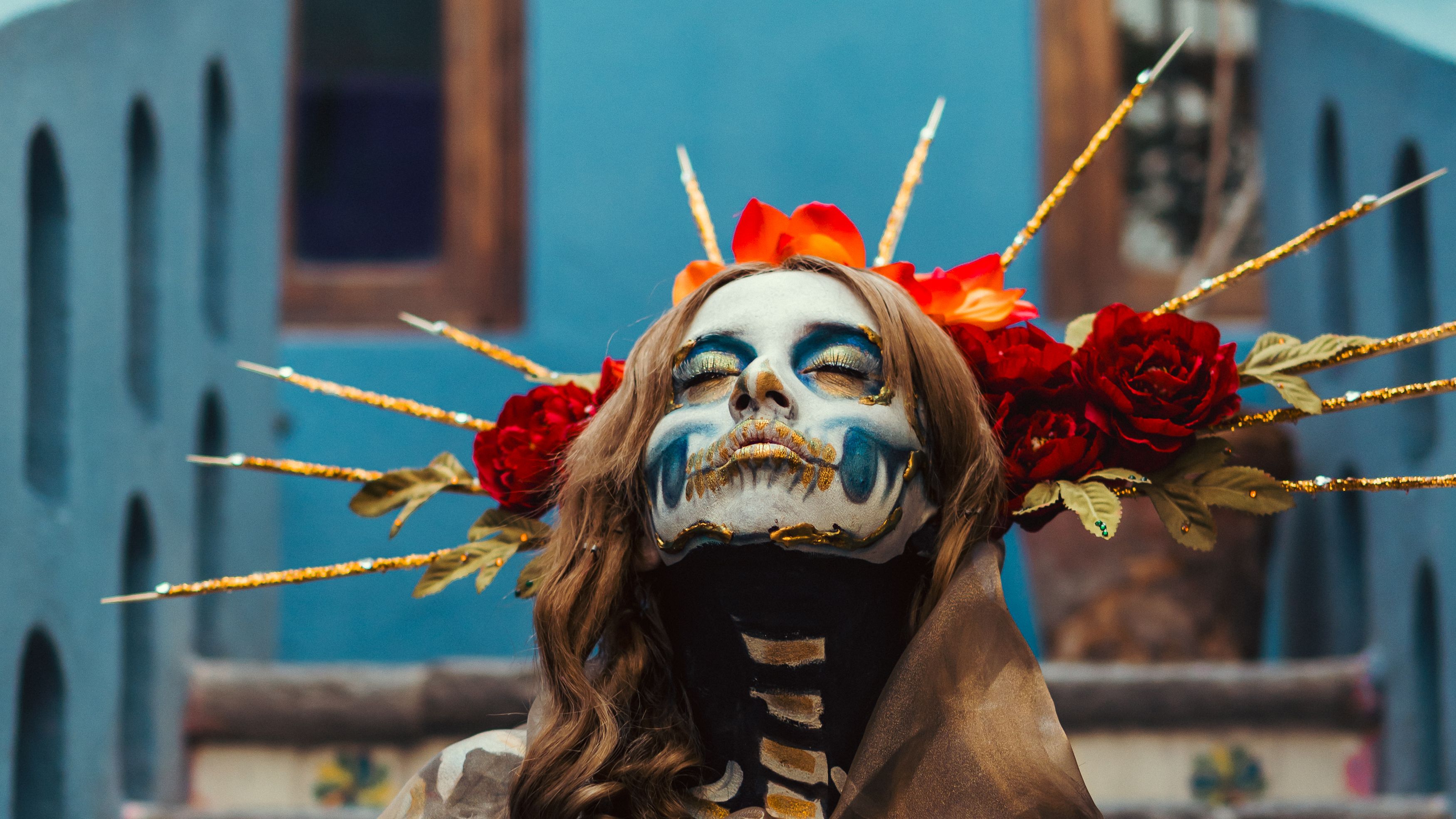 Close-up of a woman with Catrina makeup and floral headdress, representing Day of the Dead.