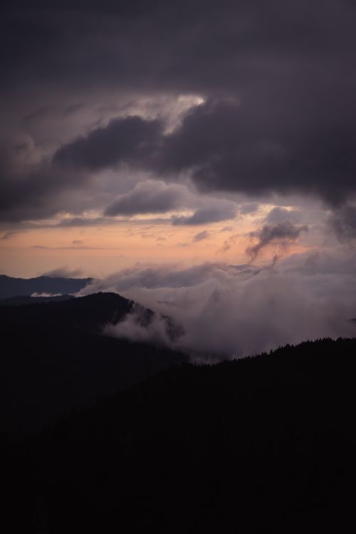 Free A breathtaking view of mountains under dramatic clouds and twilight sky. Stock Photo