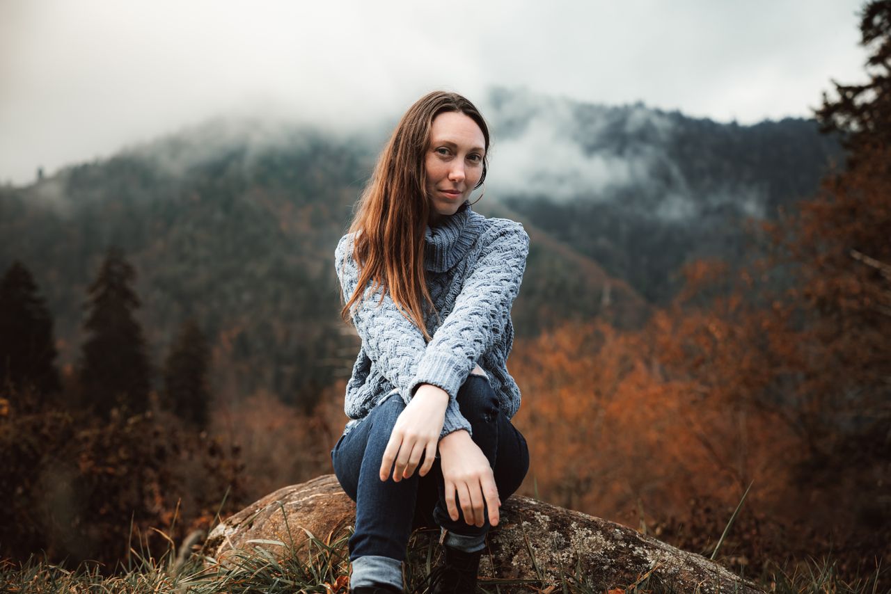 a woman in a blue sweater enjoying the misty and atmospheric autumn mo