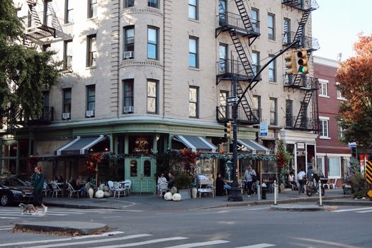 Street corner cafe in New York City with outdoor seating, typical urban architecture, and foot traffic.