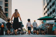 阳光明媚的日子里，一家人推着婴儿车、牵着狗，走过热闹的户外市场街