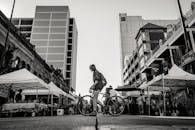 一张熙熙攘攘的城市街头市场的黑白照片，照片中有人推着自行车，周围是各种摊位