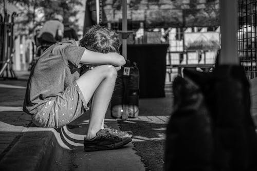 Foto Monocromatica Della Persona Seduta Sul Marciapiede