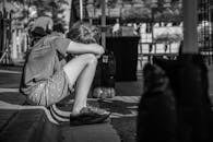 一个孩子独自坐在路边，在单色的城市环境中显得孤独而沉思