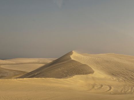 Serene desert dunes under a clear sky, capturing natural beauty and tranquility.