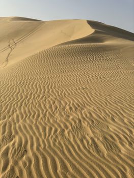 Captivating view of serene sand dunes with textured patterns under a clear sky.