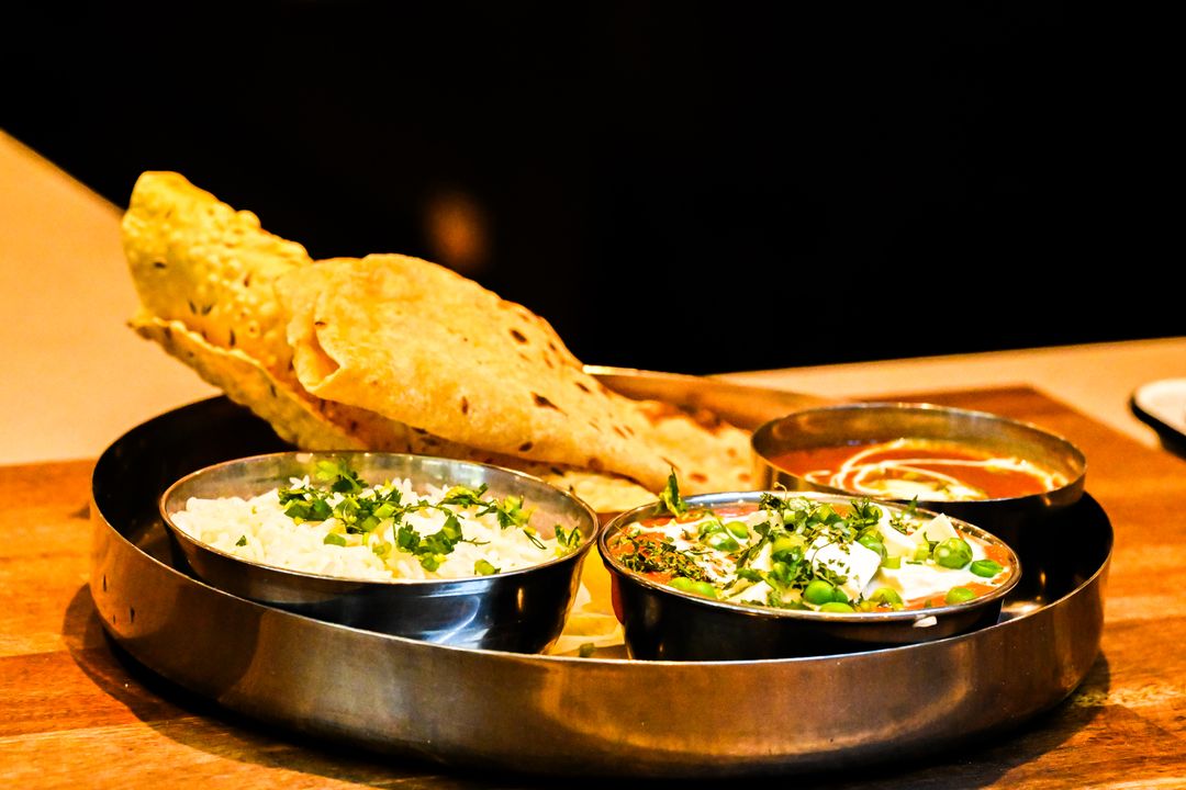 Jain Food Culture in Gujarat: How a Community Shaped an Entire Cuisine 1 A traditional Indian thali with multiple vegetarian curries, naan, and accompaniments representing Gujarati-Jain cooking.