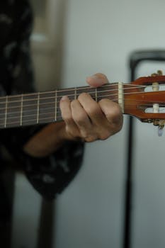 A close-up image capturing a hand strumming an acoustic guitar.