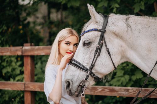 Free A woman lovingly interacting with a white horse outdoors. Stock Photo