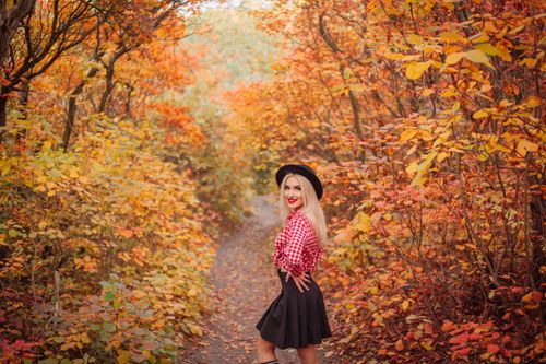 Free A woman in stylish fall attire walks through a vibrant autumn forest. Stock Photo