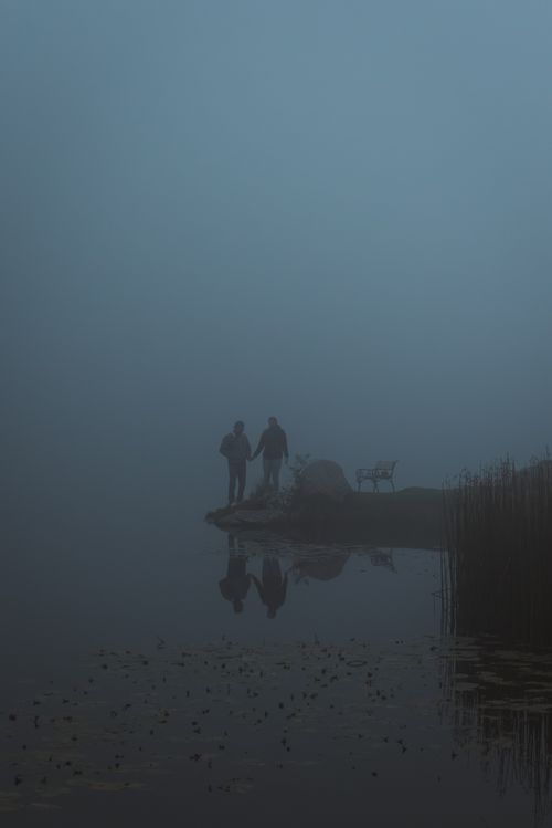 Free Couple holding hands on a misty lake shore in Styria, Austria, evoking tranquility and solitude. Stock Photo