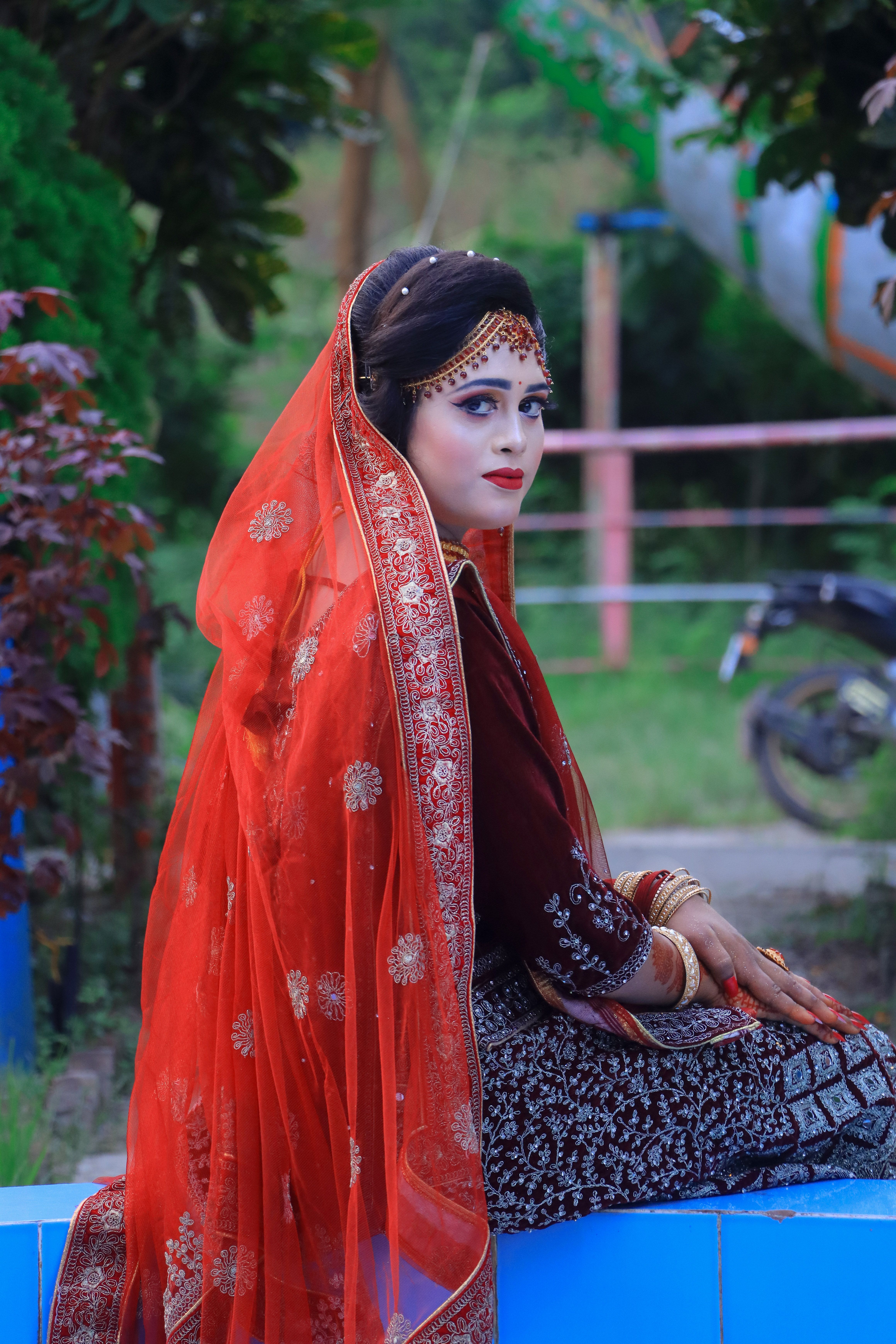 A graceful bride in traditional attire posing elegantly outdoors.