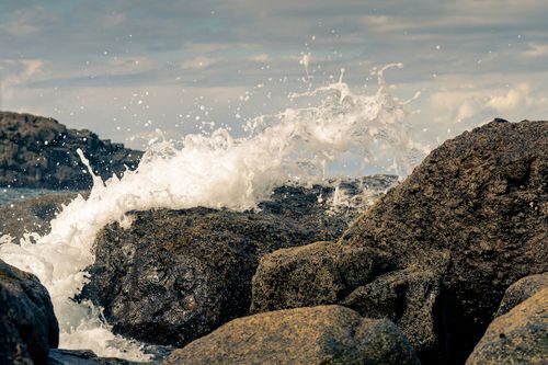 Free Captivating scene of ocean waves splashing against rugged rocks, evoking nature's power. Stock Photo