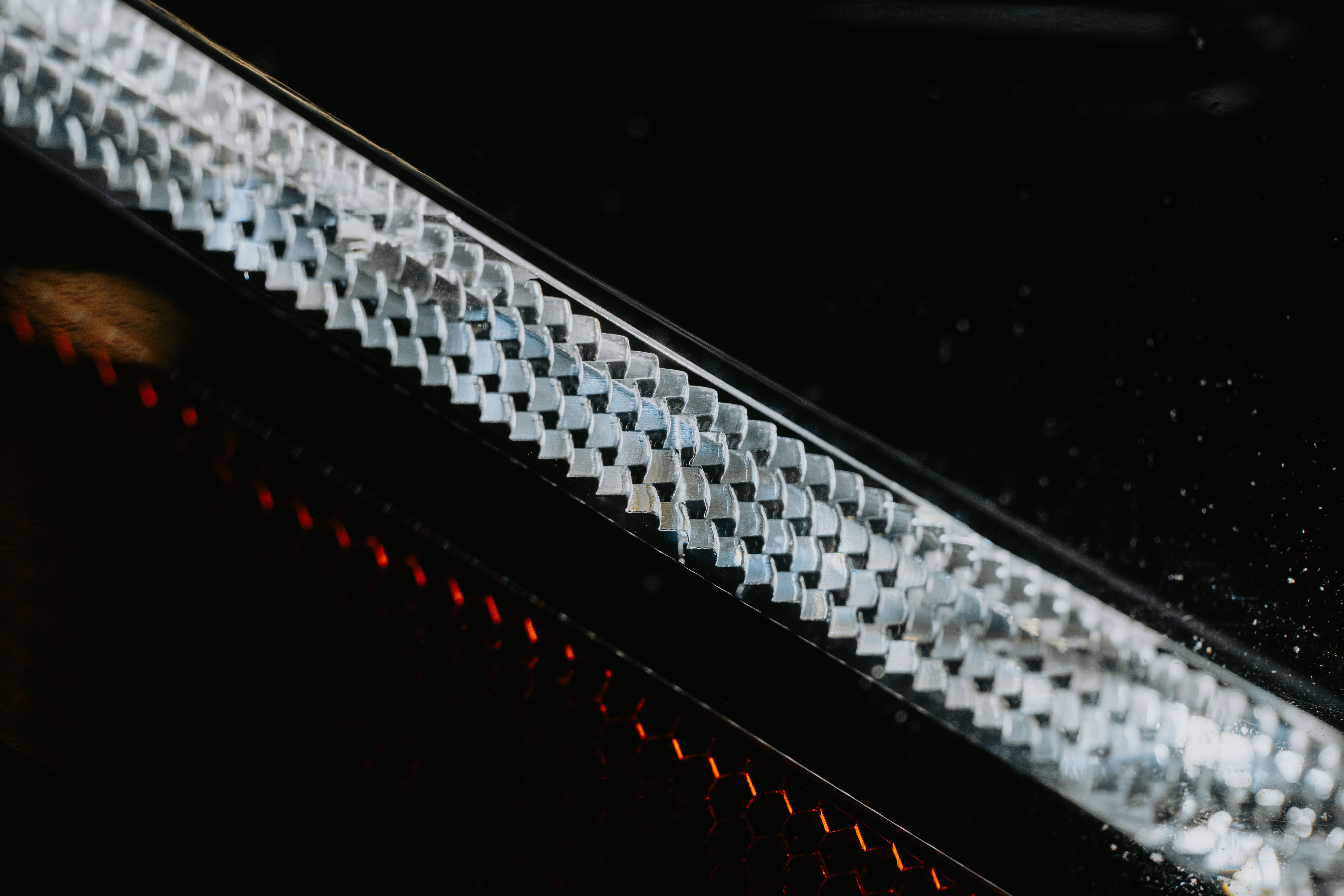 Detailed macro shot of a textured metallic pattern with light reflections.