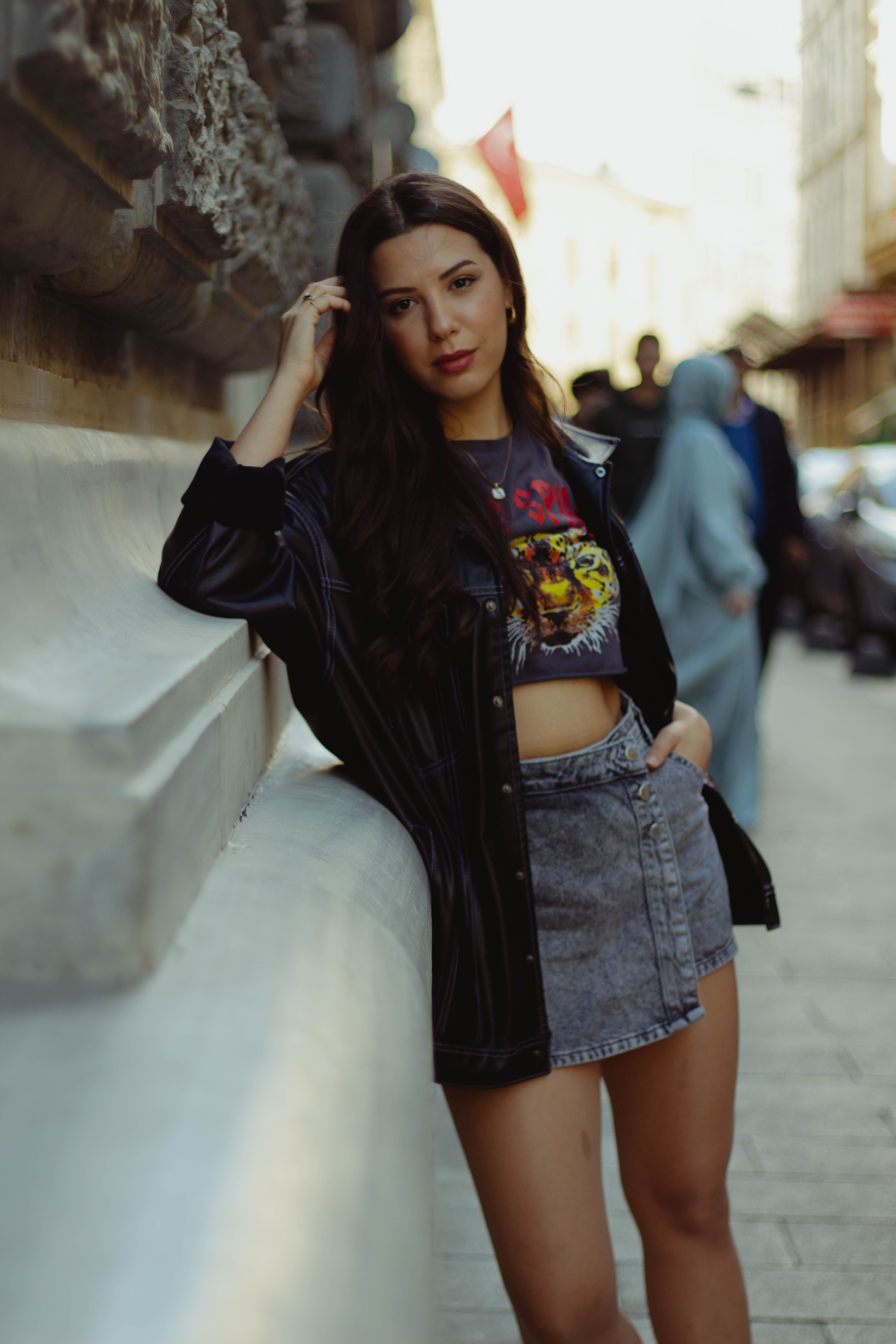 Young woman in trendy outfit posing against historic architecture in Istanbul.