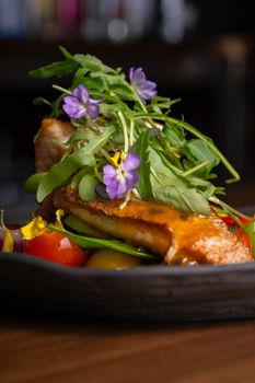 A gourmet dish featuring grilled salmon topped with arugula and edible flowers.