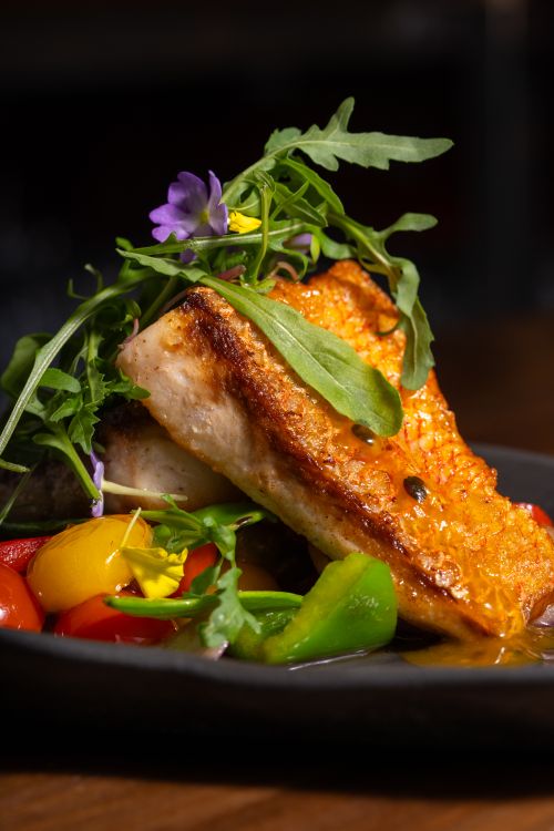 Free Delicious grilled salmon served with fresh vegetables, herbs, and vibrant flowers. Stock Photo