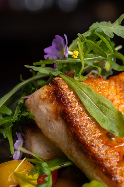 Free Juicy grilled salmon served with fresh greens and vibrant flowers for a gourmet presentation. Stock Photo