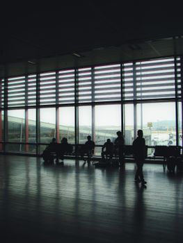 Silhouette of travelers waiting in Ankara airport terminal. Captures ambiance of waiting and travel.