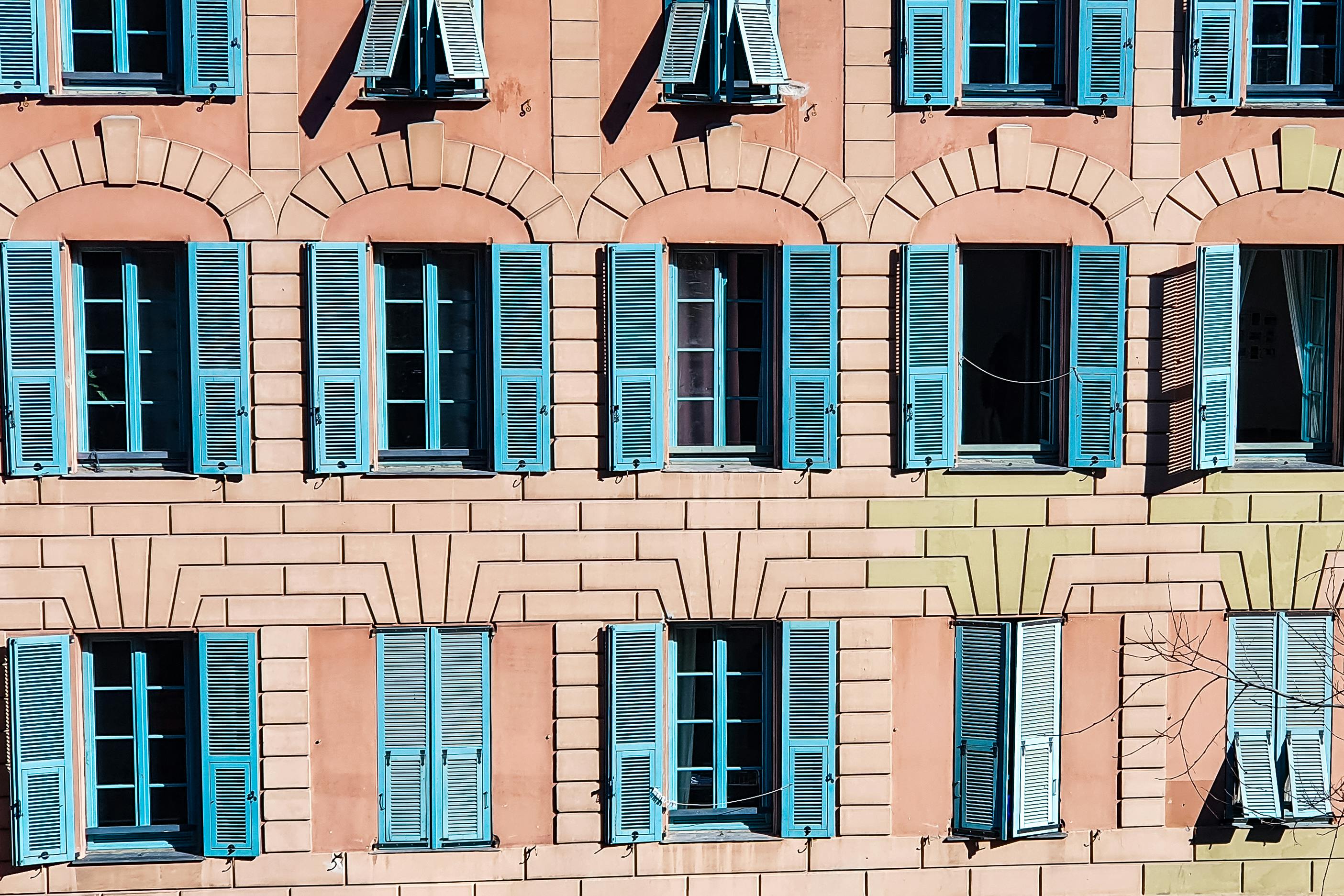 Vibrant facade with blue shutters on a historic building in Nice, France, capturing Mediterranean architecture.