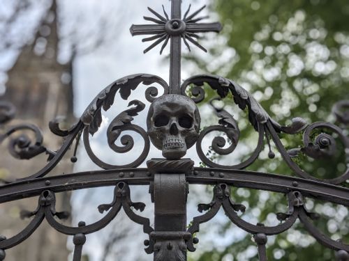 Free Close-up of ornate wrought iron gate with skull and cross detail, outdoors. Stock Photo