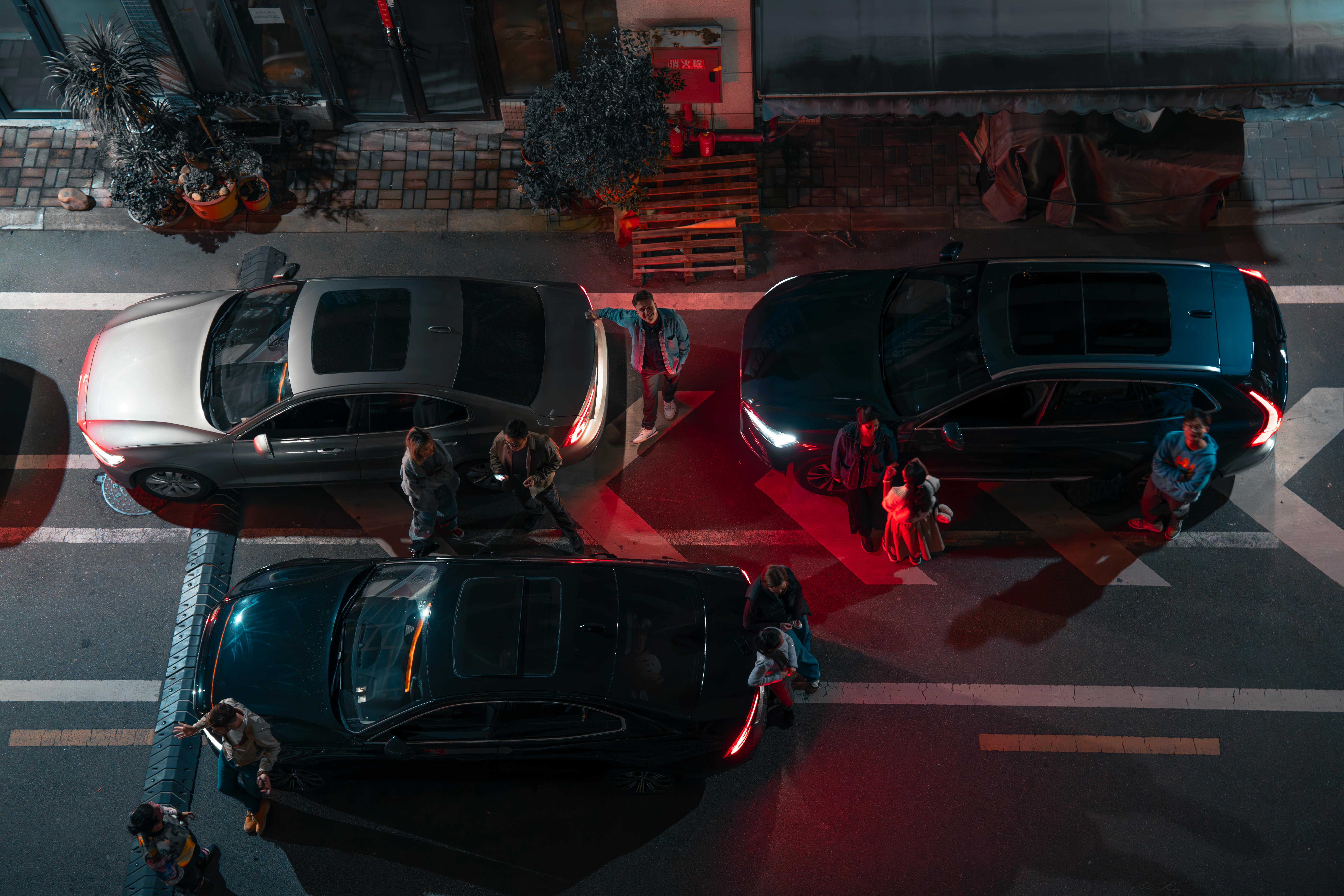 Aerial view of people and cars on a city street at night, illuminated by streetlights.