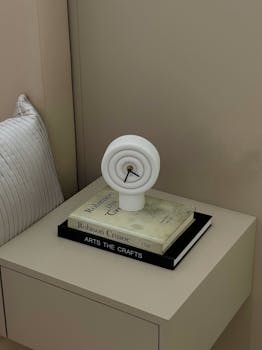 Stylish minimalist bedside table featuring a modern abstract clock and books for decor inspiration.