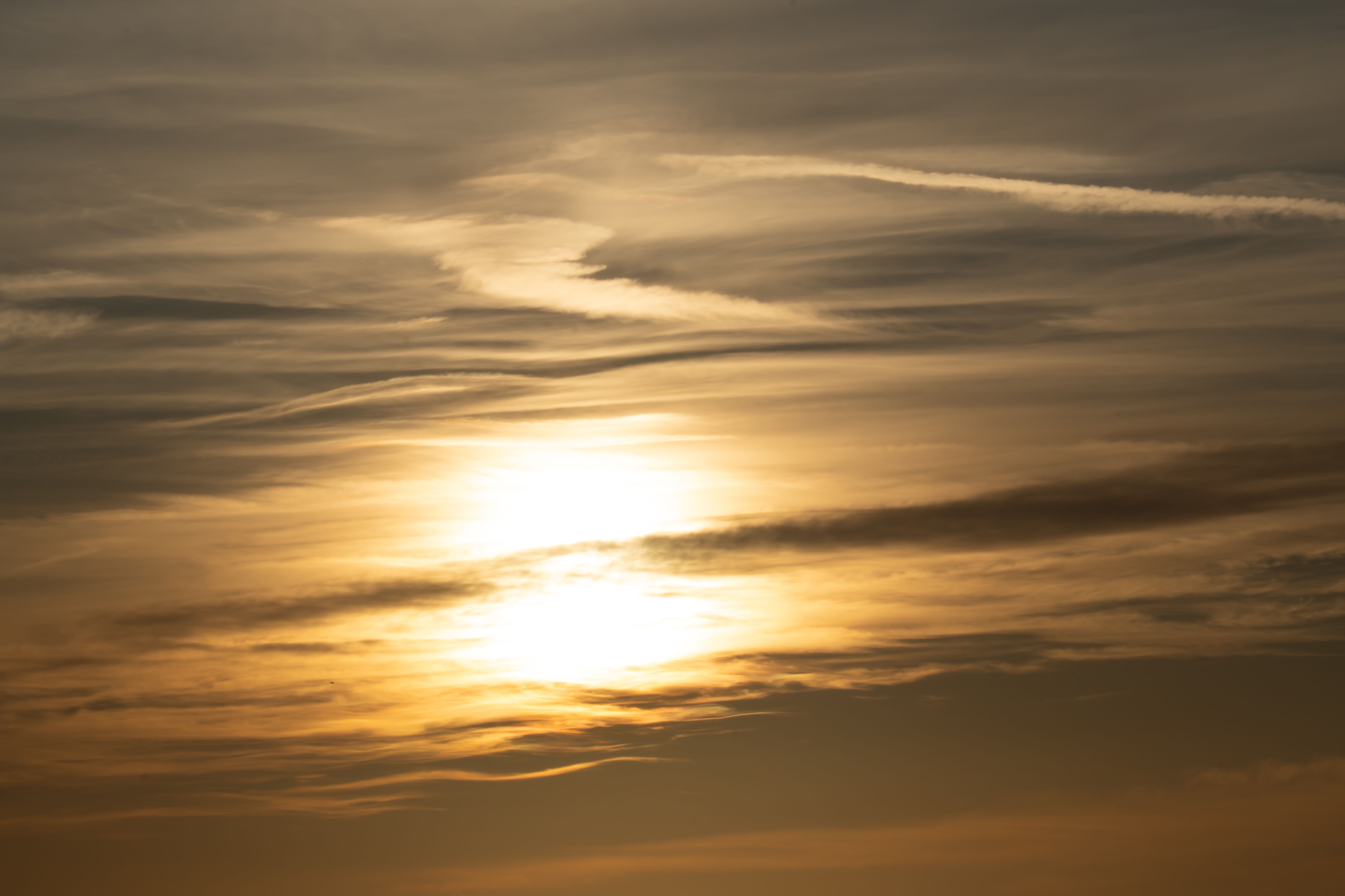 Golden sunset with dramatic cloud formations in a serene sky.