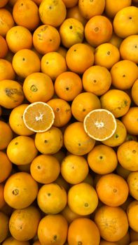 A vibrant assortment of fresh oranges with two halves, showcasing texture and color.