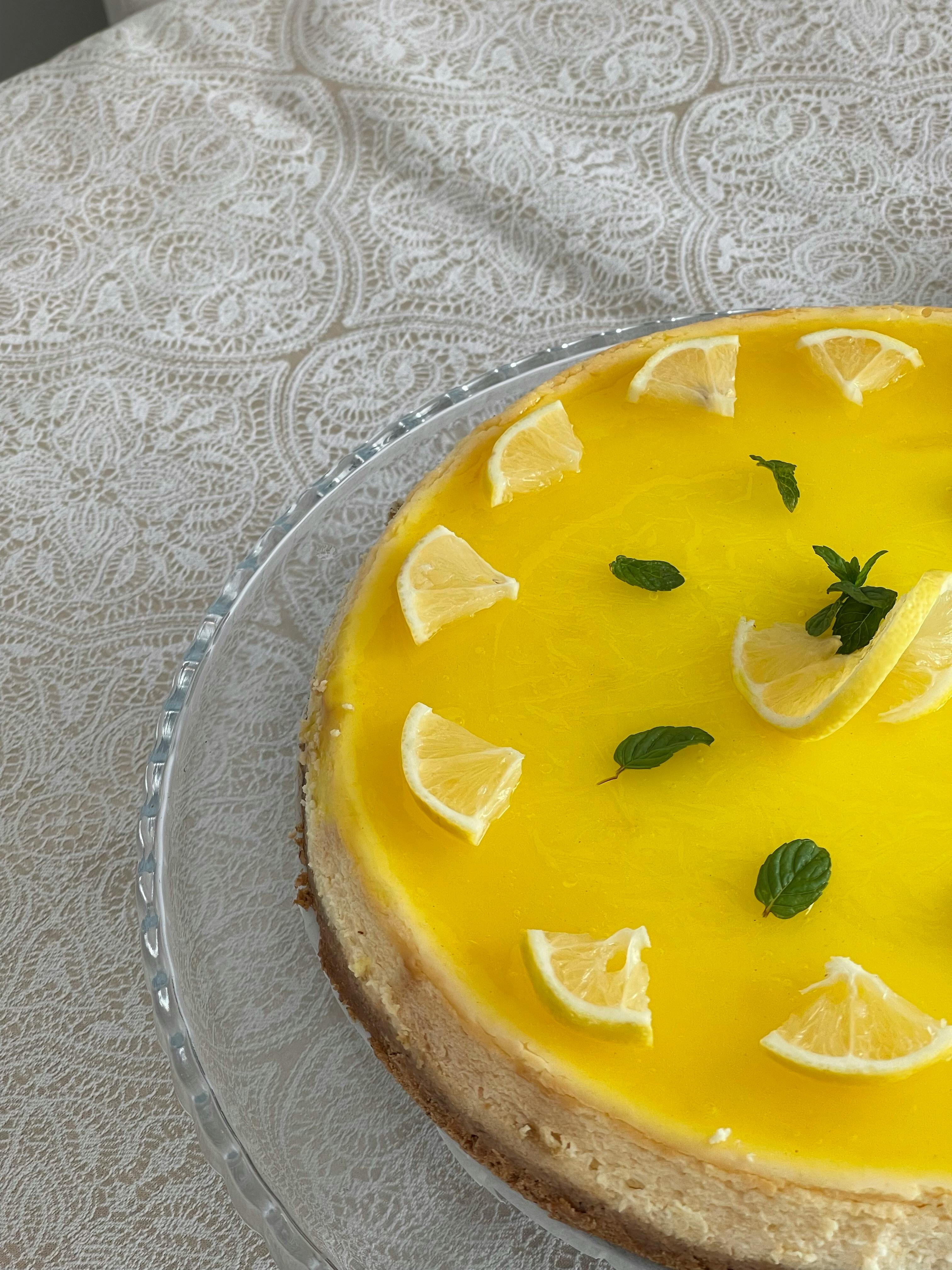 Delicious lemon cheesecake with fresh lemon slices and mint on lace tablecloth.