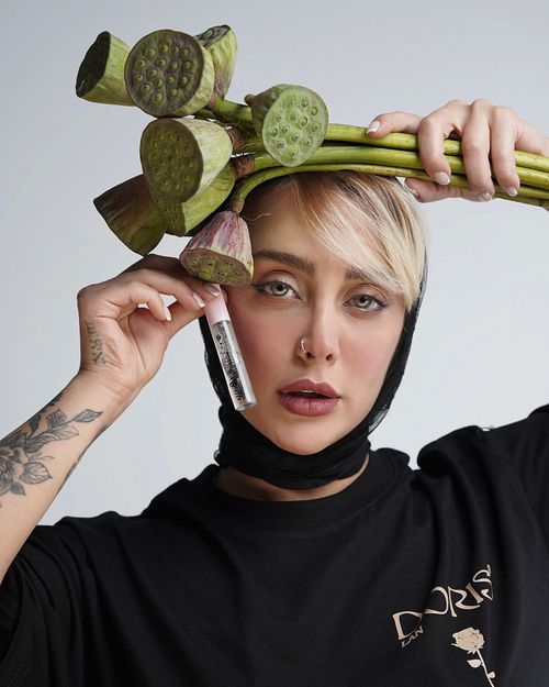 Free Stylish model posing with lotus pods and lipstick in a creative fashion portrait. Stock Photo