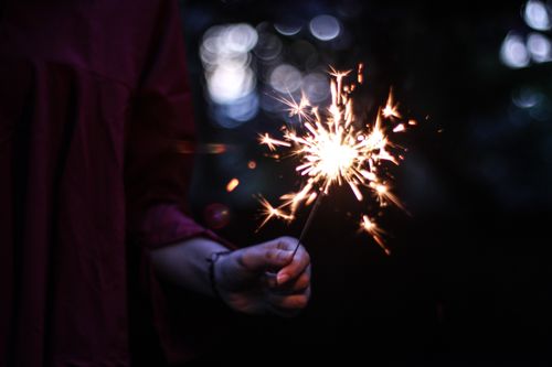 Free A person holding a sparkling sparkler against a dark bokeh background. Stock Photo