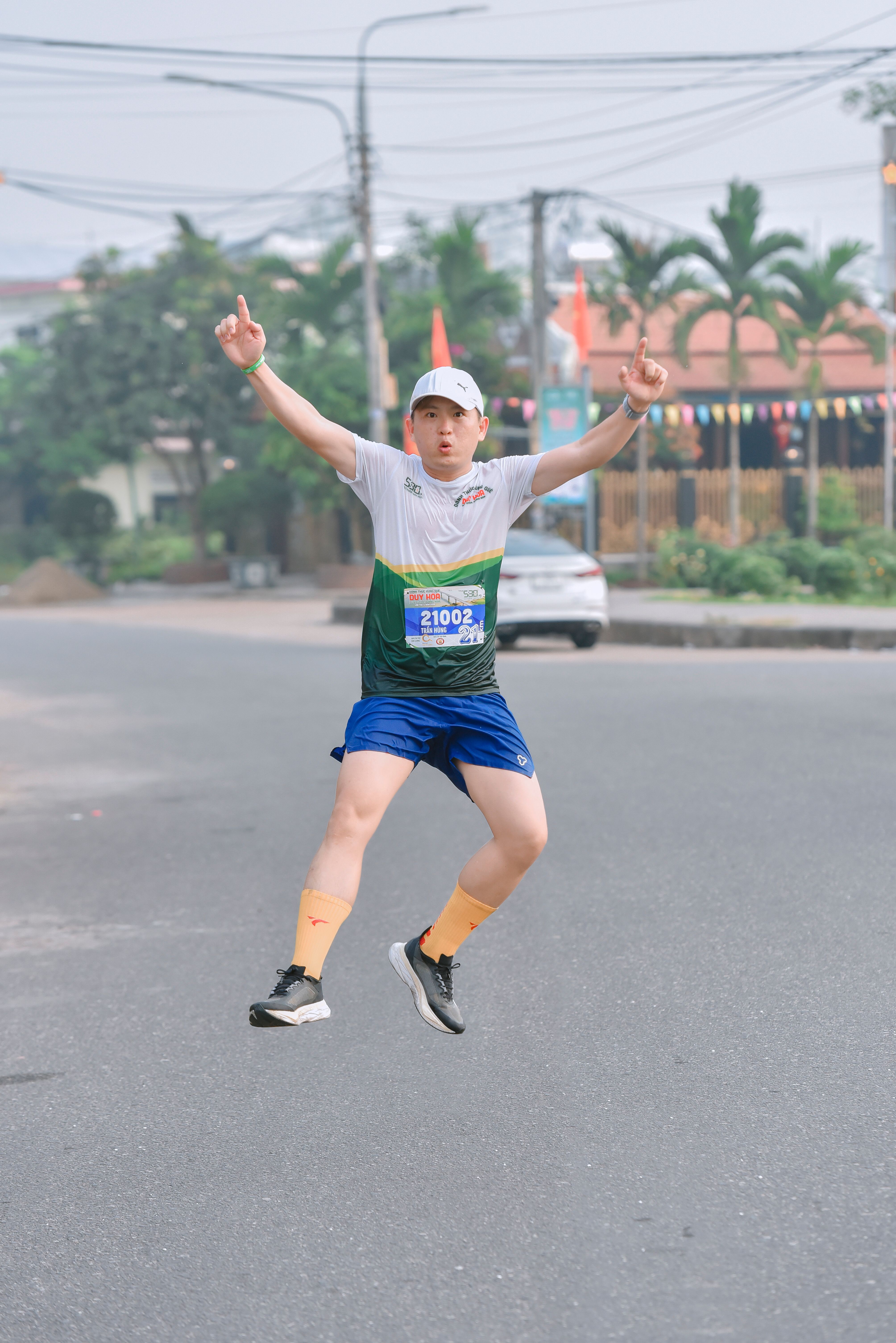 A male marathon runner in motion, jumping energetically on a city street.