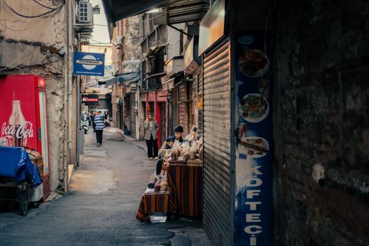 A bustling narrow street with colorful local vendors and pedestrians.