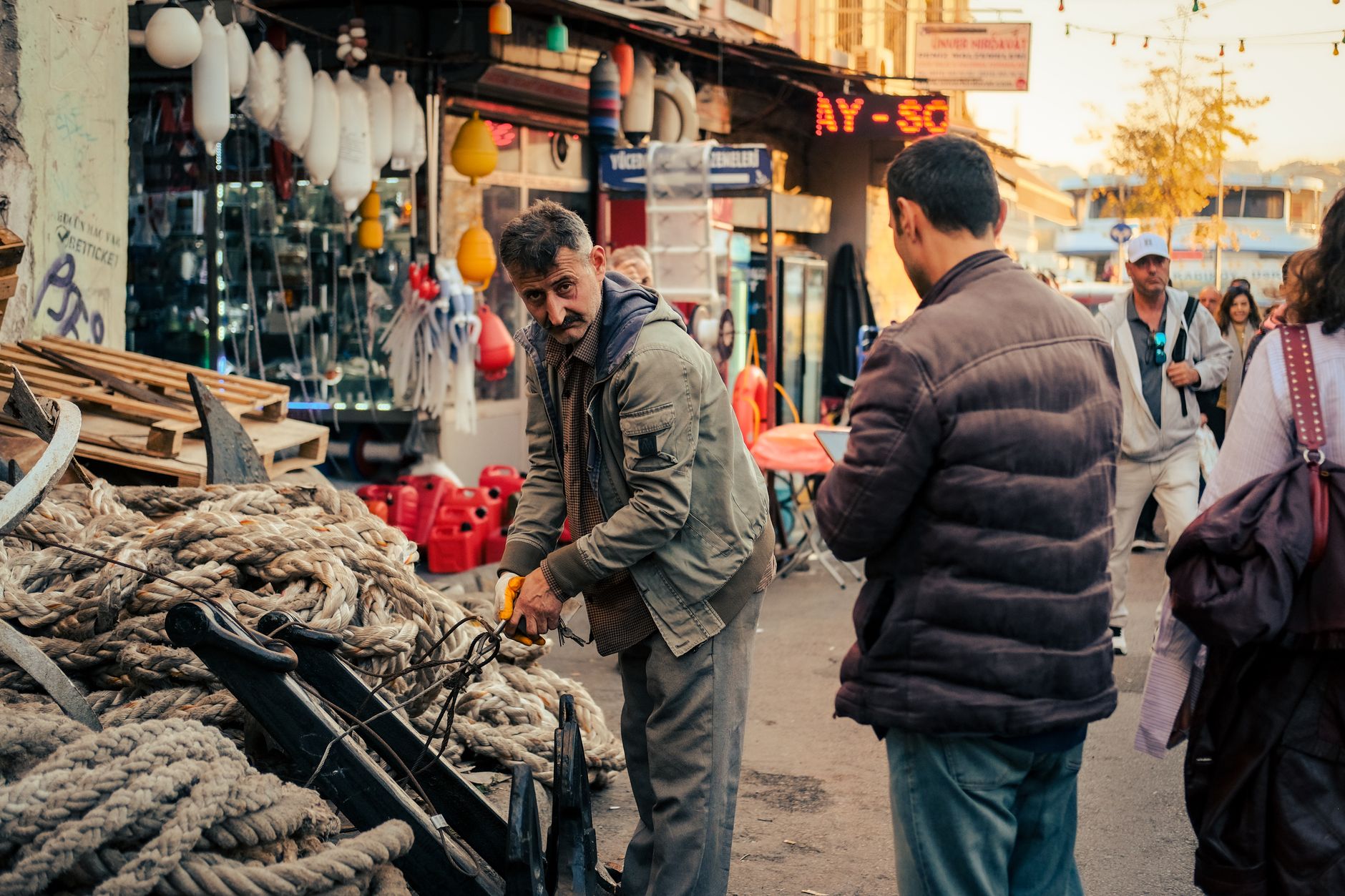 Man working with ropes amidst busy market scene